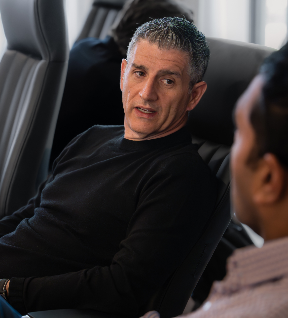 A Herringbone leader in a black sweater talking with a colleague in the foreground